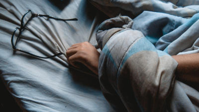 Image of arm and glasses in bed